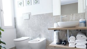 Un bany modern amb vàter, bidet, rentapel i barra de tovalloles.