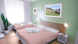 Habitació d'hotel amb dos llits, una planta en test, un quadre amb marc i una taula de nit amb una làmpada.