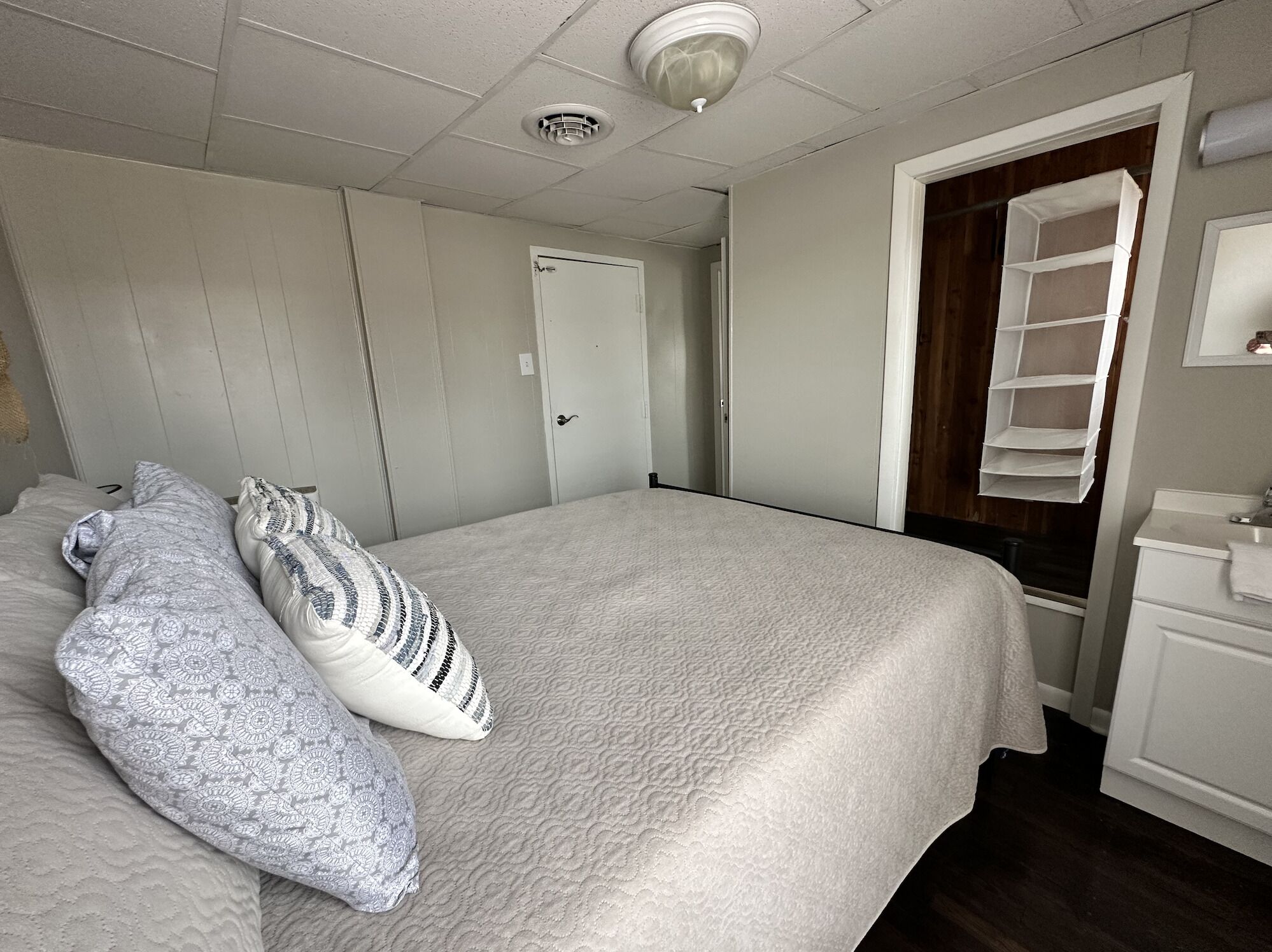 Un dormitorio con cama, almohadas, armario, espejo y estante.