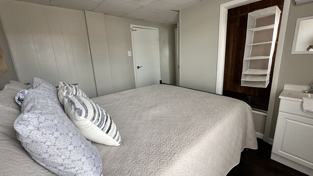 A bedroom with a bed, pillows, a wardrobe, a mirror, and a shelf. - Newly renovated 2 bdrm apartment in downtown (24) (Coshocton)