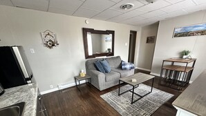 A modern living room with a grey sofa, a coffee table, and a kitchen area with a sink and countertop. - Newly renovated 2 bdrm apartment in downtown (24) (Coshocton)