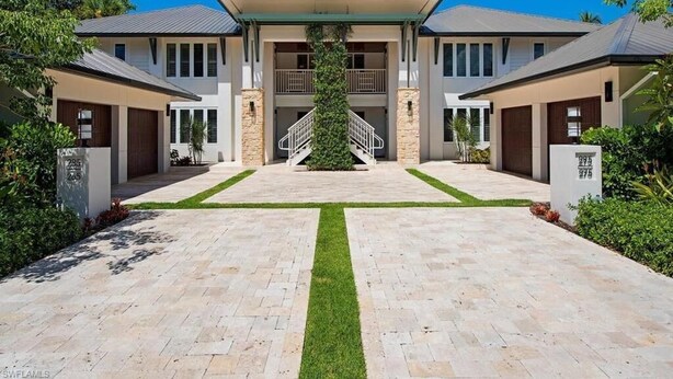 A modern two-story house with a central staircase, a covered front porch, and a well-maintained front yard.