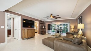 A spacious living room with a large sofa, a television, and a ceiling fan.