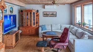 A living room with a wooden cabinet, a television, a sofa, and a chair.