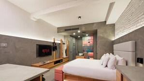 Un dormitorio moderno con cama, televisión, escritorio y armario.