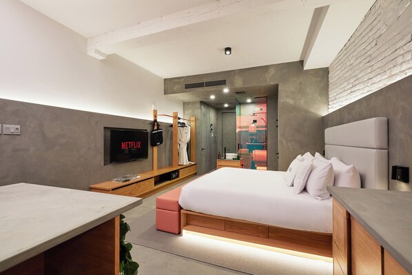 Quarto moderno com cama, televisão, escrivaninha e guarda-roupa.