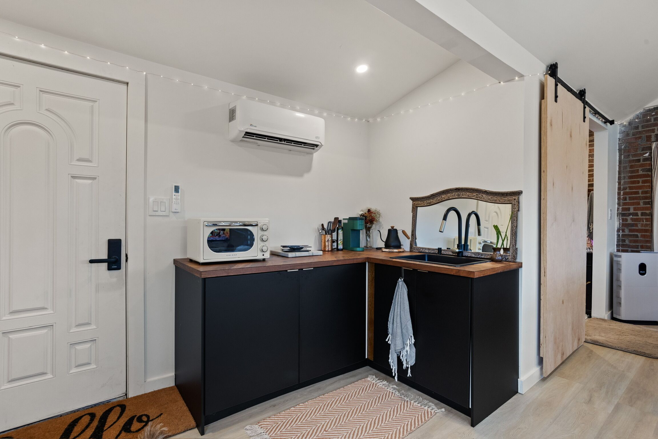 A compact kitchen with a built-in microwave, a sink, and a hanging towel.
