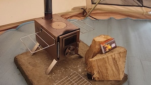 A tent with a wood-burning stove, a metal rack, and a log. - Dog Friendly Cozy Bell Tent With Log Burner (Gaerwen)