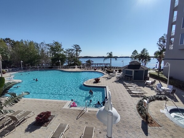 A swimming pool with a view of the sea, surrounded by lounge chairs and a small gazebo. - Lakefront Corner 2 Bedroom 2 Bathrooms Lakefront Condo - 1 mile to Disney World (Orlando)
