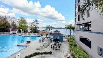 A pool area with a hot tub, lounge chairs, and a view of the water.