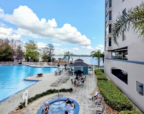 A pool area with a hot tub, lounge chairs, and a view of the water. - Lakefront Corner 2 Bedroom 2 Bathrooms Lakefront Condo - 1 mile to Disney World (Orlando)