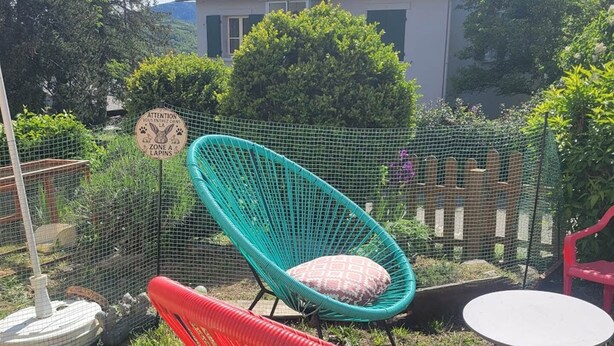 Un espacio al aire libre rodeado de una valla, con una silla, una mesa y un letrero.