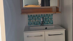 A bathroom with a white sink, a mirror above it, and a tiled backsplash.