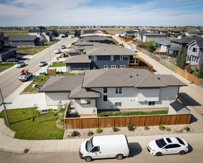 Un quartier résidentiel composé de plusieurs maisons à deux étages, une rue bordée de voitures garées et un panneau de signalisation bien visible.
