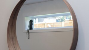 A round mirror on a wall with a window reflection.