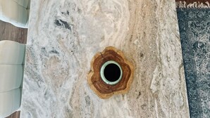 Una mesa con cubierta de mármol y un agujero en el centro, rodeada de dos sillas.