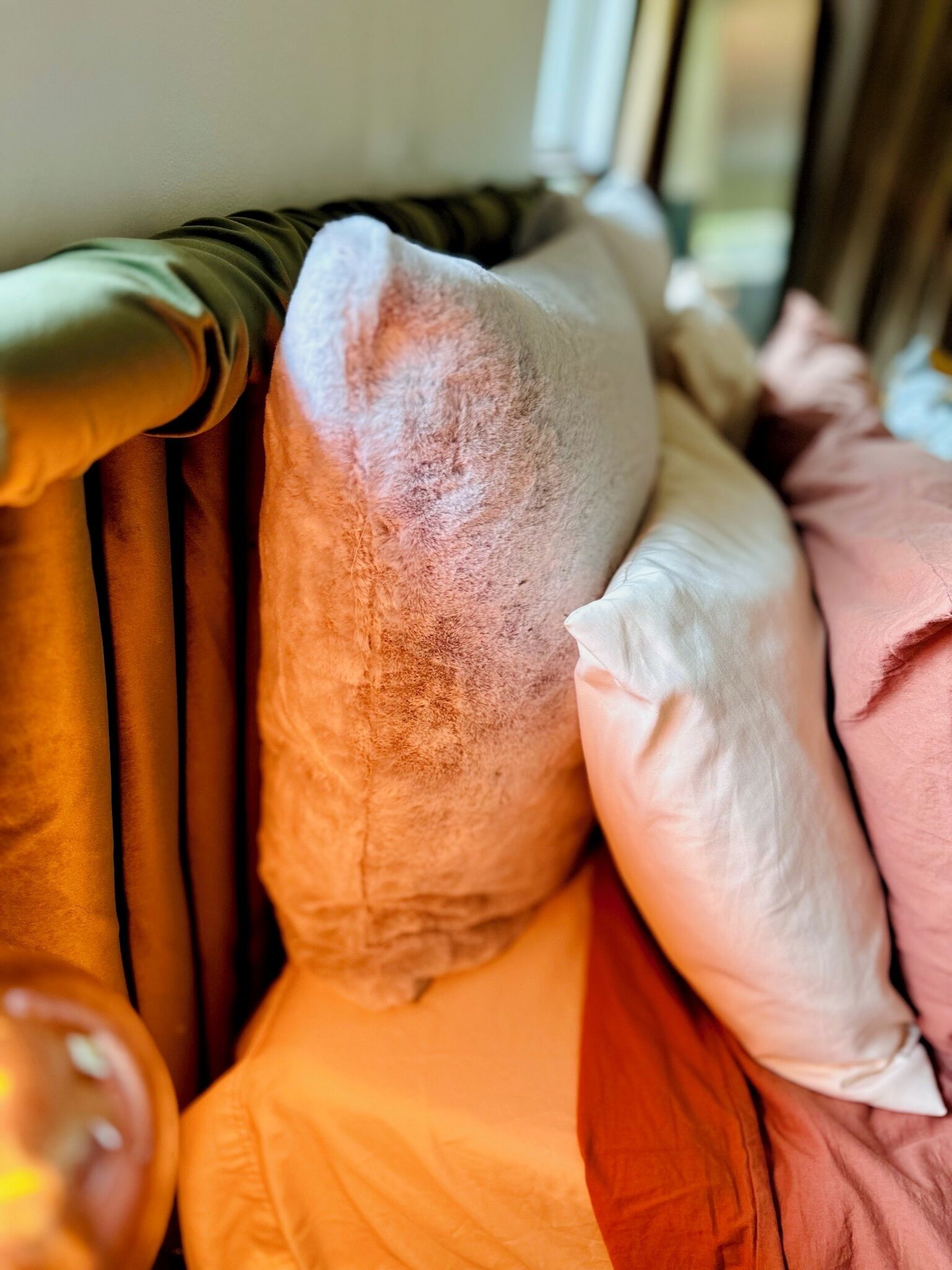 Primer plano de una cama con varios almohadones y una colcha a rayas.