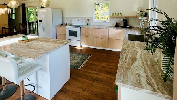 Una cocina moderna con una isla central, armarios de madera y un amplio ventanal.