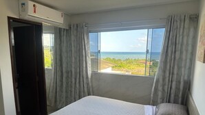 A bedroom with a bed, a window with curtains, and an air conditioning unit.