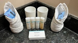 Productes de bany com xampú, condicionador, loció corporal i una caixa de sabó de bany damunt una superfície de marbre.
