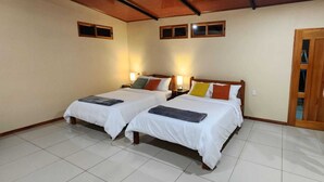 Una habitació d'hotel amb dos llits, ambres de fusta i terra de rajola.