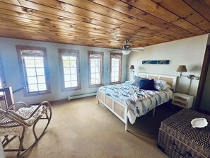 Ein Schlafzimmer mit einem Bett, einem Schaukelstuhl, einer Korbus und einem Deckenventilator.