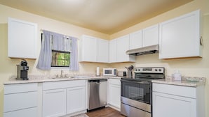 A modern kitchen with white cabinets, stainless steel appliances, a dishwasher, and a microwave.