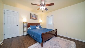 A bedroom with a wooden bed, two bedside lamps, a ceiling fan, and a patterned rug.