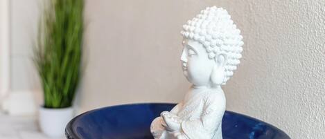 Una estatua blanca de Buda sentada en un cuenco azul.