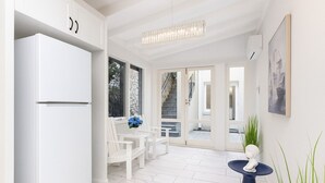 A modern kitchen with white cabinetry, a built-in refrigerator, and a dining area with white chairs and a blue vase. - The Hamptons Paddington Home (Paddington)