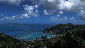 Un paisaje costero con vista al mar, una pequeña isla y una zona montañosa con edificios.
