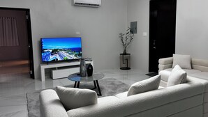 Una sala moderna con una televisión de pantalla plana, un sofá, una mesa de centro y una planta en maceta.
