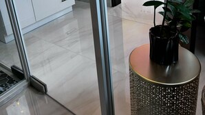 Un baño moderno con puerta de vidrio, lavamanos con espejo y una planta en maceta.