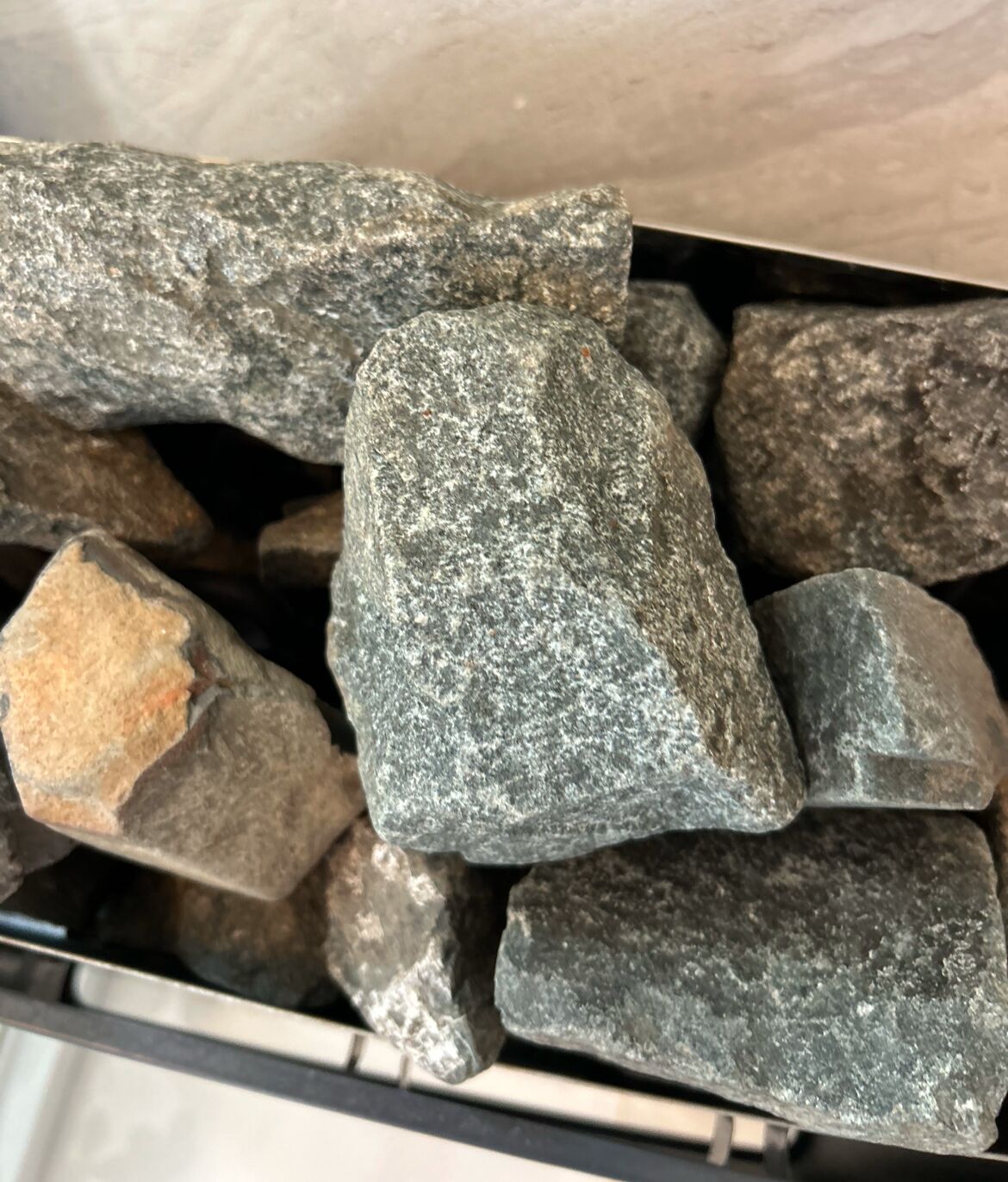 Uma coleção de pedras irregulares e rústicas em um recipiente de metal.
