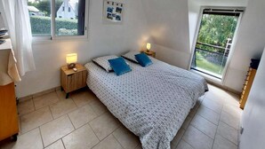 Un dormitorio con una cama, dos mesitas de noche, una ventana y un ventilador de techo.