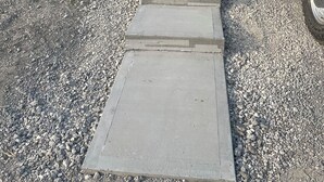 Ein Weg führt zu einem Haus mit Garage, einem parkenden Lastwagen und einem Kiesplatz.