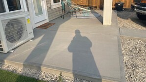 Eine Beton-Terrasse mit Holzlattenzaun, Gartenmöbeln und einem geparkten Fahrzeug.