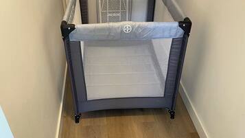 A room with a wooden floor, a grey playpen, and a white door.