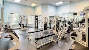 A gym with various exercise equipment, including dumbbells, benches, and weight machines.
