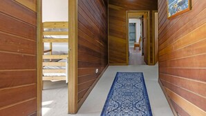 A narrow hallway with wooden walls and a blue patterned rug.