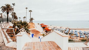 A beachside hotel with outdoor seating, palm trees, and a view of the sea. - Beach House By Gt House (Silves)