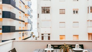 A balcony with a table set for two, a chair, and a potted plant. - Beach House By Gt House (Silves)