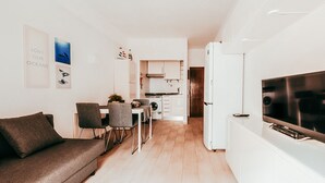 A modern living room with a sofa, dining table, chairs, and a TV. - Beach House By Gt House (Silves)