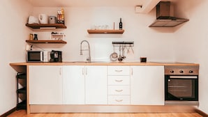 A compact kitchen with a microwave, stove, and wooden cabinets.