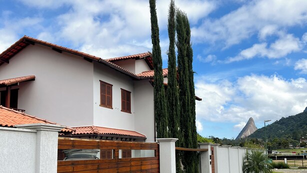 Una casa moderna con techo de tejas, una reja de madera y un camino de entrada pavimentado.
