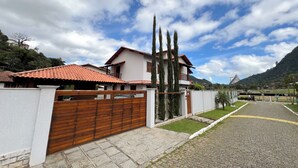Un barrio residencial con una casa que tiene techo de tejas, un portón de madera y un camino de entrada pavimentado.
