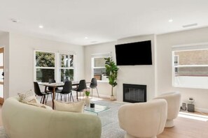 A modern living room with a sofa, a glass coffee table, and a fireplace. - Elegant Oasis | Heated Pool & Spa | 5mi to Beach (Long Beach)