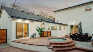 A backyard with a hot tub, patio furniture, and a covered seating area. - Elegant Oasis | Heated Pool & Spa | 5mi to Beach (Long Beach)