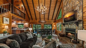 A cozy log cabin interior with a fireplace, a dining area, and a living room furnished with a sofa and a coffee table. - *Riverhouse on the Cartecay*WaterFront~Tube~Family (Ellijay)