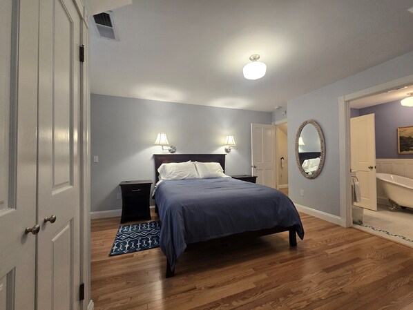 Un dormitorio con cama, lámparas de noche, un espejo y un baño con bañera.